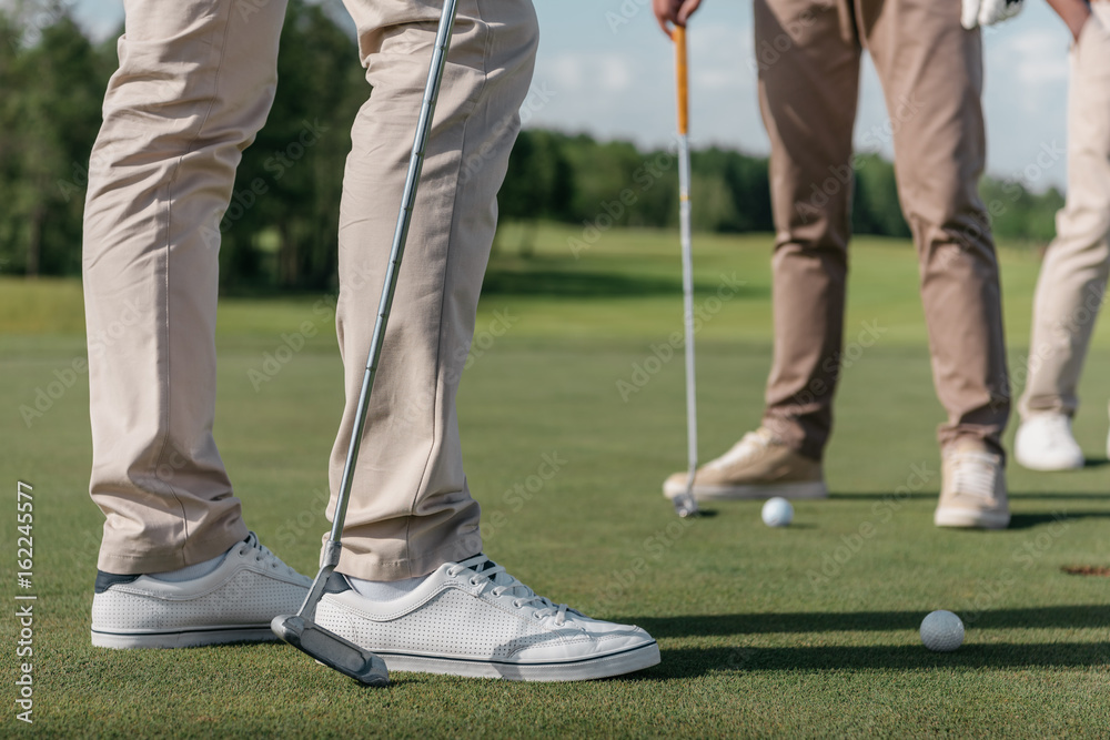Obraz premium cropped shot of professional golf players getting ready to shot a ball