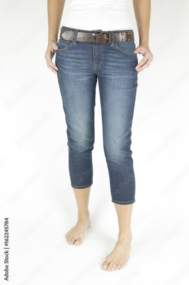 Slim woman in fashionable pants stands against a white background Slim woman in fashionable pants stands against a white background