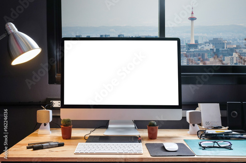 Graphic designer's workspace equipped with a pen tablet, a computer and white screen for text with beautiful city view from the window