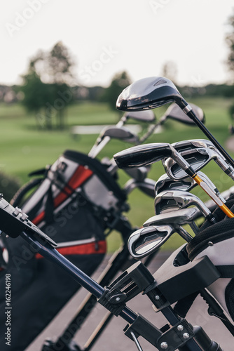 Close-up view of shiny golf clubs in golf bags outdoors