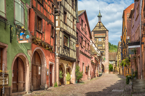 Fototapeta Naklejka Na Ścianę i Meble -  Central street of Riquewihr village with colorful traditional half-timbered french houses and Dolder Tower, Alsace, France