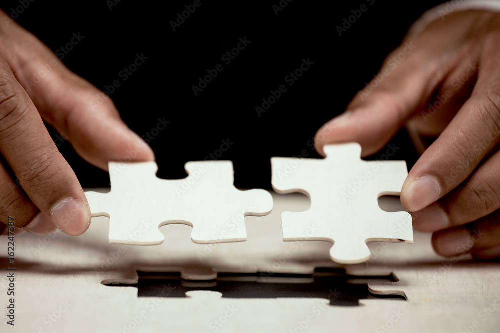 Businessman hand put the last piece of jigsaw puzzle to complete the mission. Business success, solutions and strategy concept Businessman hand put the last piece of jigsaw puzzle to complete the mission. Business success, solutions and strategy concept