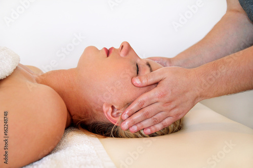 Massage of head and face in spa center. Massage wellness studio. Happy young woman enjoying face and collar area massage getting spa treatment in salon. Facial energy massage. Body and health care.