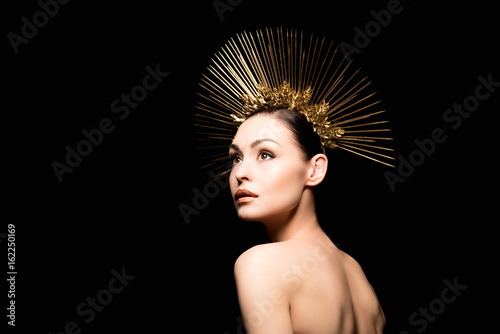 stylish naked lady in golden headpiece looking away isolated on black