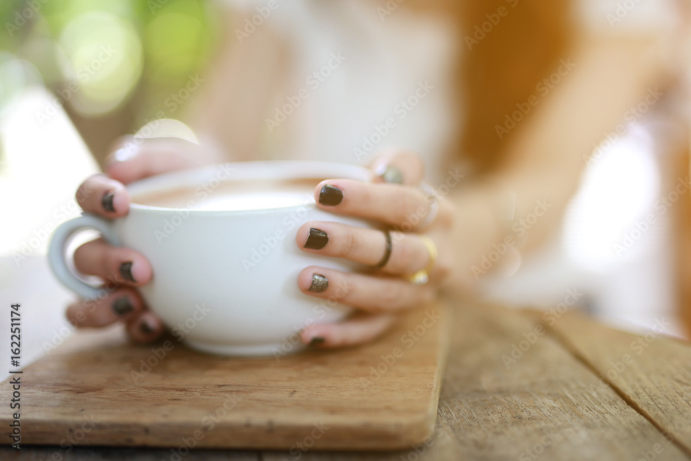Beautiful hipster woman touch a coffee cup at cafe while drinking coffee, Relaxing holiday concept. Selective focus a cup. Beautiful hipster woman touch a coffee cup at cafe while drinking coffee, Relaxing holiday concept. Selective focus a cup.