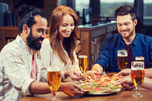 friends eating pizza with beer at restaurant