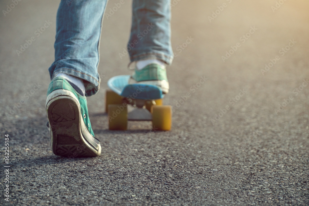 young boy wear jeans and green shoes is skateboarding on the street,selective focus and vintage tone