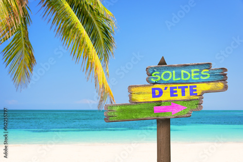 Soldes d'été, écrit sur un panneau en bois coloré, sur fond de plage tropical photo