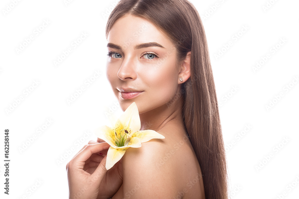 Beautiful young girl with a light natural make-up and perfect skin with flowers in her hand. Beauty face. Picture taken in the studio on a white background. Beautiful young girl with a light natural make-up and perfect skin with flowers in her hand. Beauty face. Picture taken in the studio on a white background.