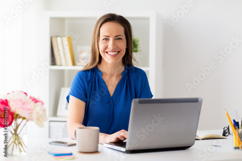 happy woman with laptop working at home or office