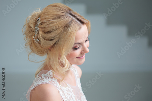 Portrait of a beautiful girl in a wedding dress. Bride in a luxurious dress on a white background  beautiful hairstyle