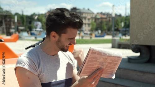 Handsome man checking news in the gazette and looks very happy, steadycam shot
