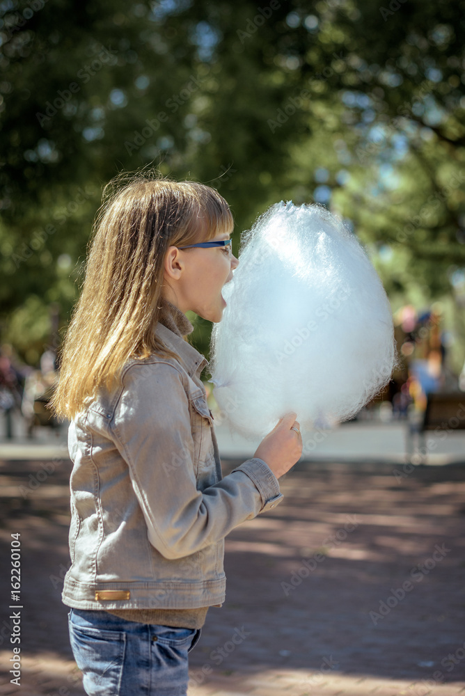 Happy teenager girl eating cotton candy in Park Happy teenager girl eating cotton candy in Park
