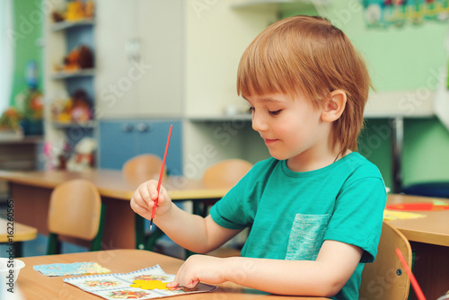 Cute little boy engaged in art and craft in classroom .