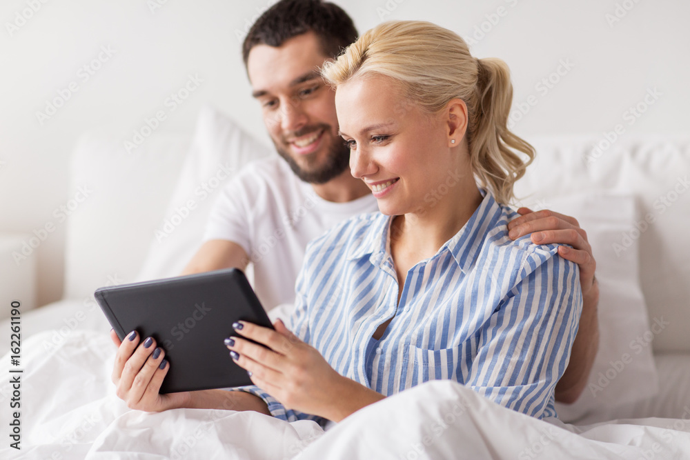 smiling happy couple with tablet pc in bed at home smiling happy couple with tablet pc in bed at home