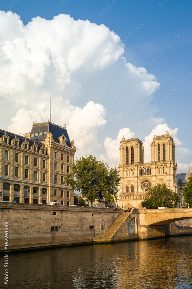 Notre-Dame cathedral in Paris and the Police headquarters under a warm sunlight with the river Seine in the foreground.