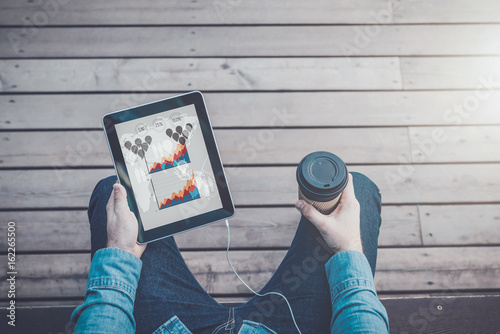 View from eyes.Close-up of digital tablet with blank screen and cup of coffee in hands of hipster man