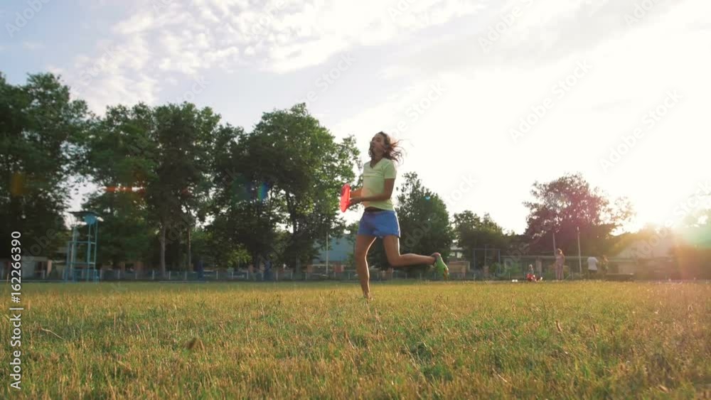 young and beautiful woman playing frisbee in the park, slow motion