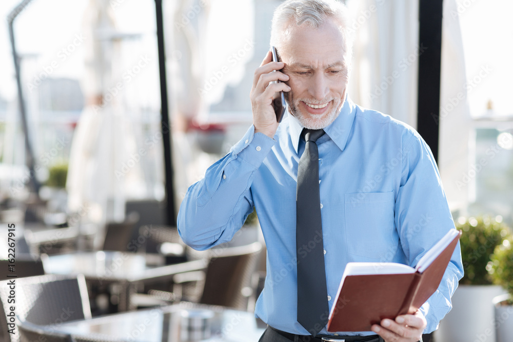 Smiling male person looking into his notebook Smiling male person looking into his notebook