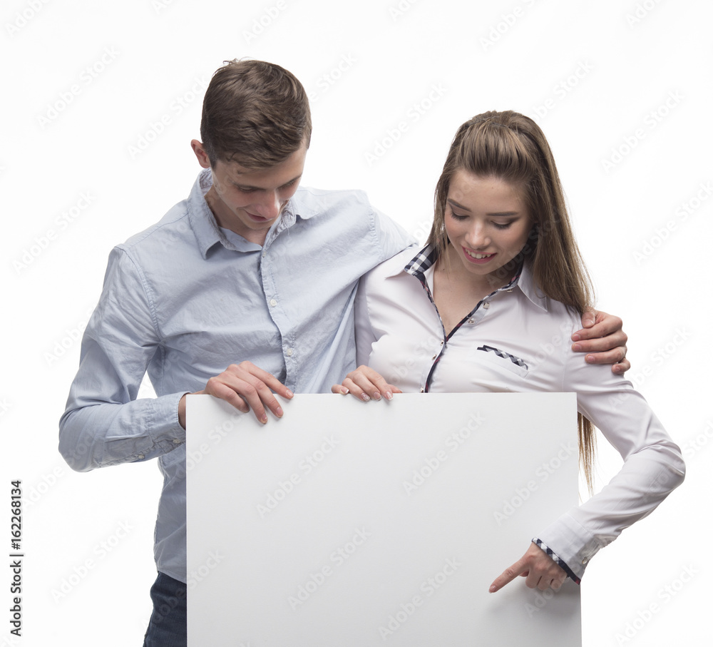 Young happy couple portrait of a confident businessman showing presentation, pointing paper placard gray background. Ideal for banners, registration forms, presentation, landings, presenting concept. Young happy couple portrait of a confident businessman showing presentation, pointing paper placard gray background. Ideal for banners, registration forms, presentation, landings, presenting concept.