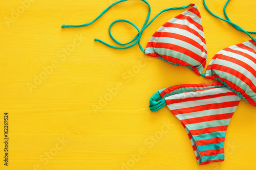 Top view of fashion female swimsuit bikini on yellow wooden background photo