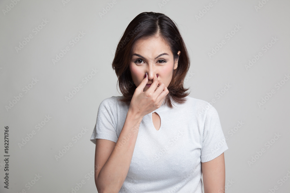 Young Asian woman holding her nose because of a bad smell. Young Asian woman holding her nose because of a bad smell.