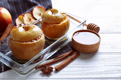 Composition with tasty baked apples and cinnamon on light wooden table, closeup photo