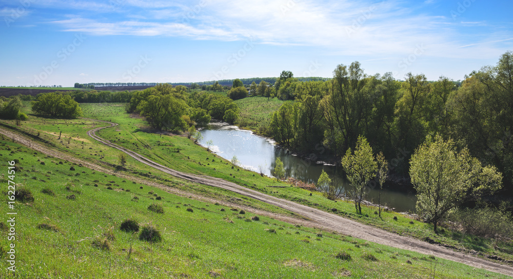 Sunny spring landscape with river and ground road