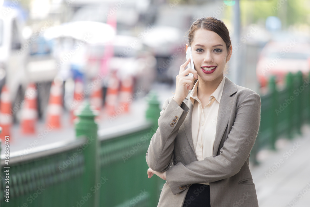 Fototapeta premium Asian businesswoman standing and using smartphome with attractive smiling, woman leader concept, 1 person, 20-28 year old.