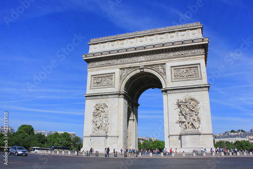 Arc de Triomphe popular top attraction in city of Paris, France. View from Champs Elysees street to Place Charles de Gaulle. Beautiful summer scene blue sky background.