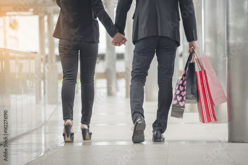 Couple In love holding Shopping Bag walking together in fashion shopping mall,beautiful woman wear high heel,enjoy after buying and walking in city street.Shopaholic Couple In love Shopping concept.