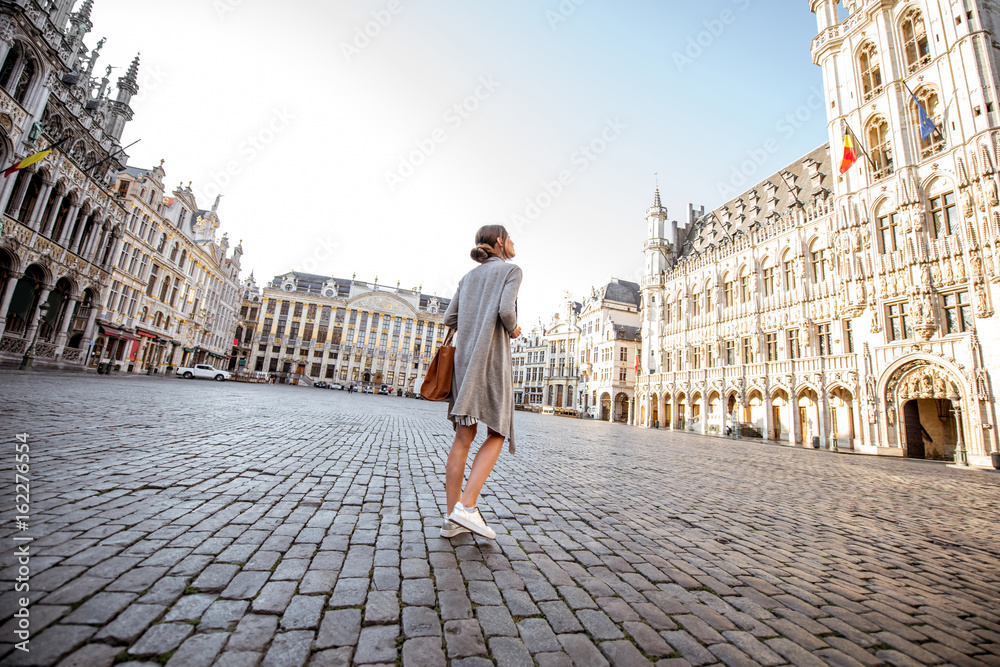 Young female tourist walking on the main square with city hall in the old town of Brussels in Belgium Young female tourist walking on the main square with city hall in the old town of Brussels in Belgium