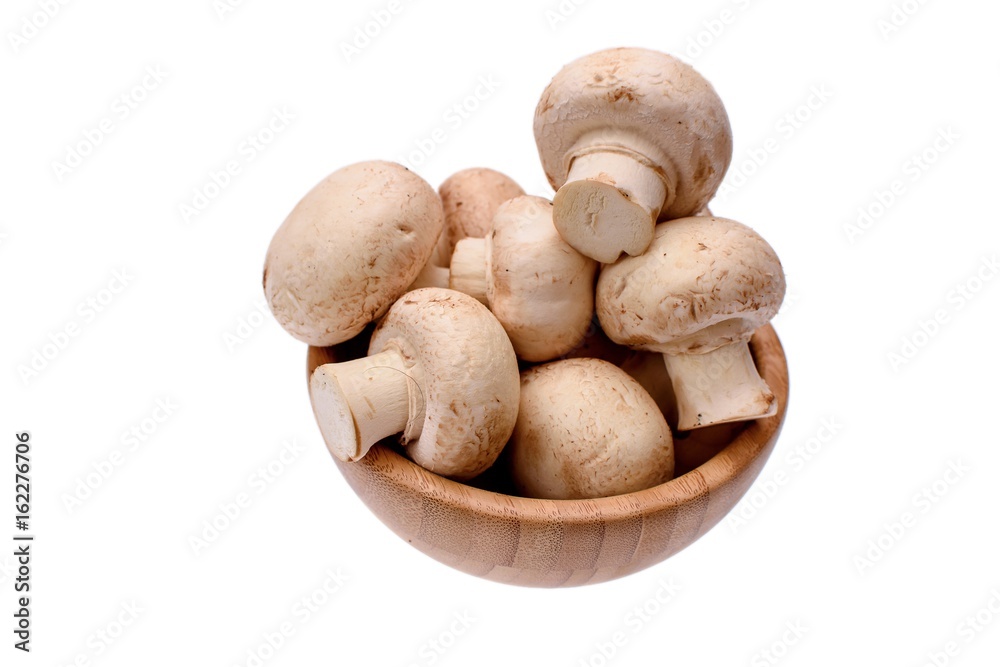 White mushrooms champignons lie in a wooden cup, isolated on a white background White mushrooms champignons lie in a wooden cup, isolated on a white background