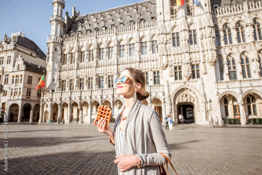 Young woman walking with waffle a traditional belgian pastry food in the center of Brussels city during the morning
