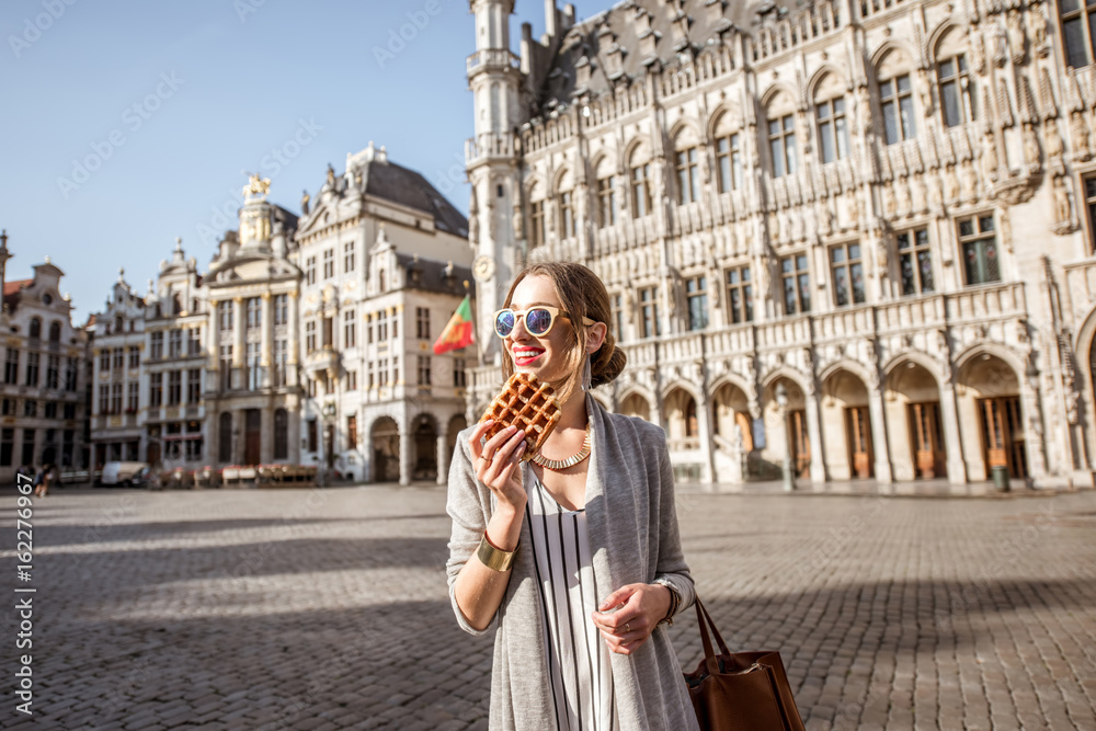 Young woman walking with waffle a traditional belgian pastry food in the center of Brussels city during the morning