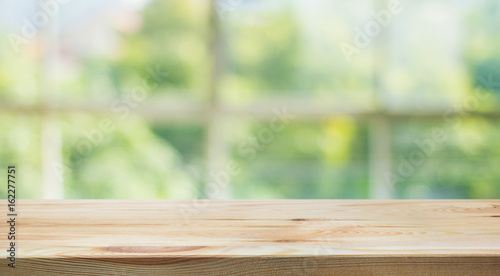 Wood table top on blur of window glass and abstract green from garden backgrounds