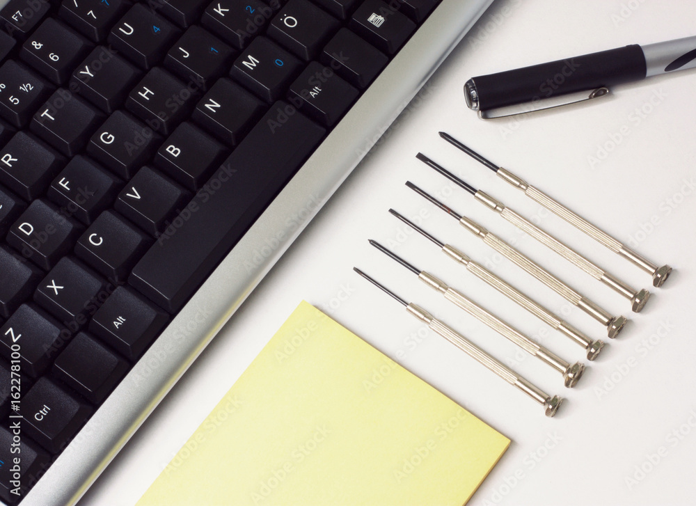 Screwdrivers and Keyboard on the White Desk Screwdrivers and Keyboard on the White Desk