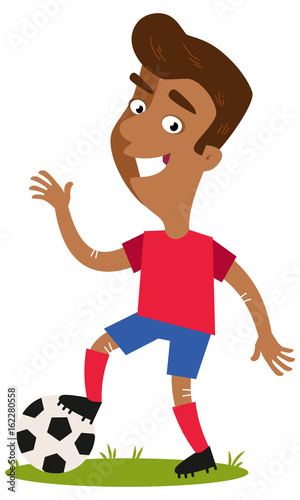 Smiling and waving asian cartoon footballer wearing red shirt and blue shorts putting one foot on the football isolated on white background.