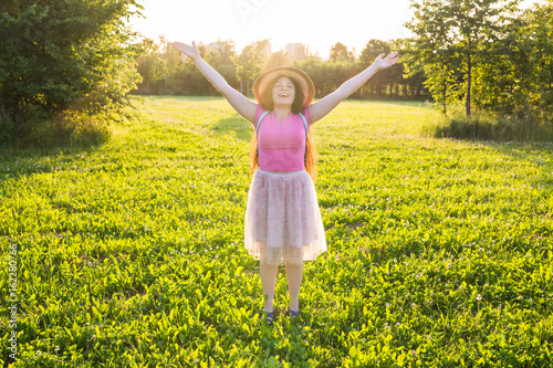 Free happy young woman raising arms watching the sun in the background at sunrise