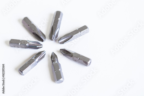 Metal bits for the screwdriver is laid out in the shape of snowflakes or stars. Bits from a screwdriver on isolated white background.