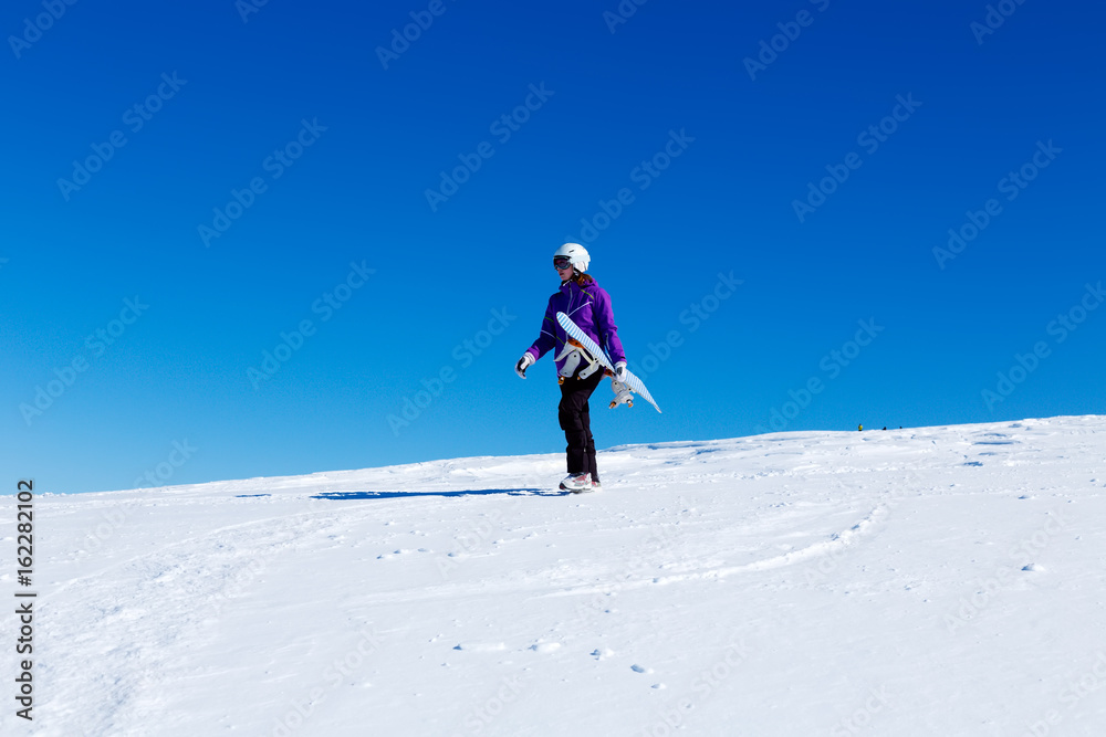 Girl with snowboard at the top of a mountain