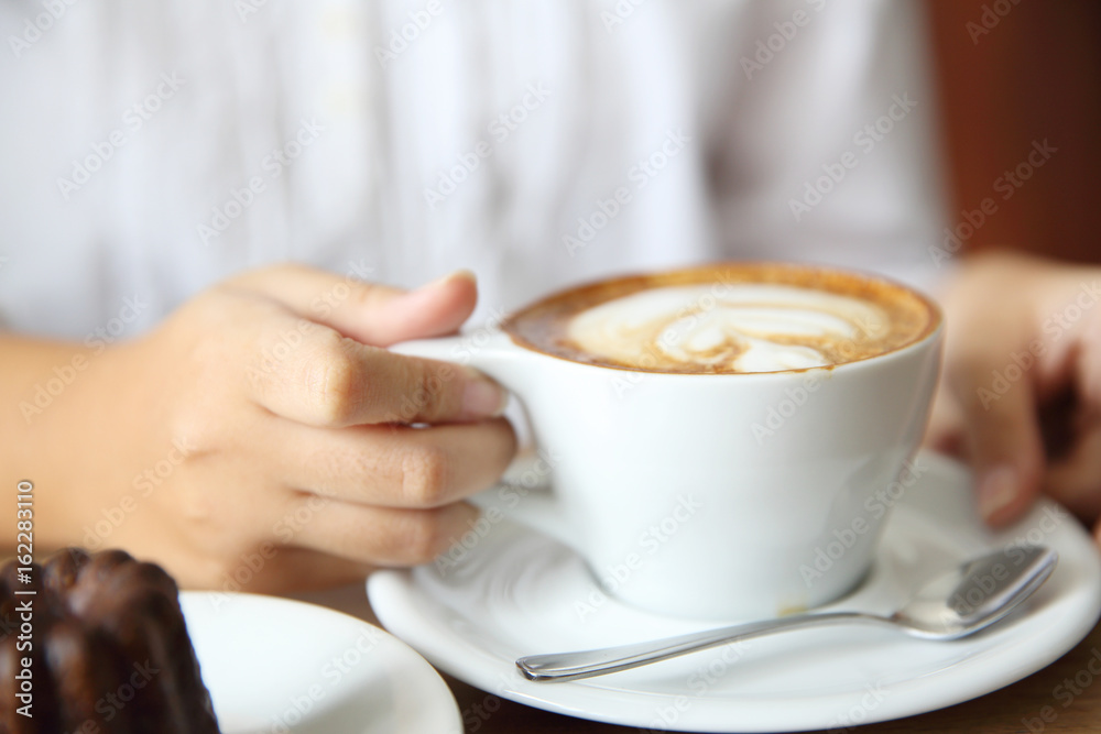 woman hands with cappuccino coffee on a wood table woman hands with cappuccino coffee on a wood table
