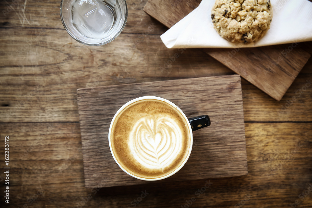 cappuccino coffee with cookie on wood background