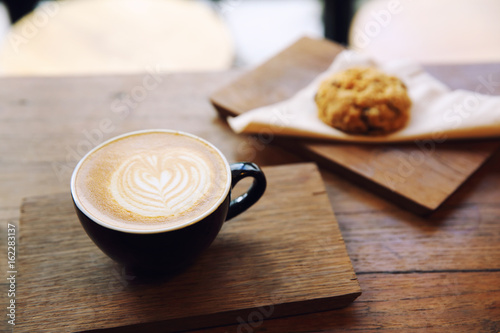 cappuccino coffee with cookie on wood background