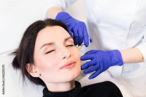 A woman on the procedure of injections in a cosmetology clinic