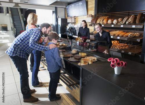 Customers at bakery counter choosing organic cake