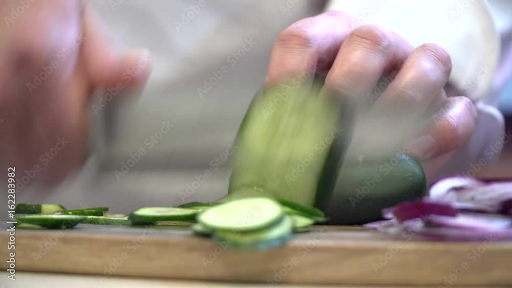 Closeup of the chef cutting cucumber on the wooden bord Closeup of the chef cutting cucumber on the wooden bord