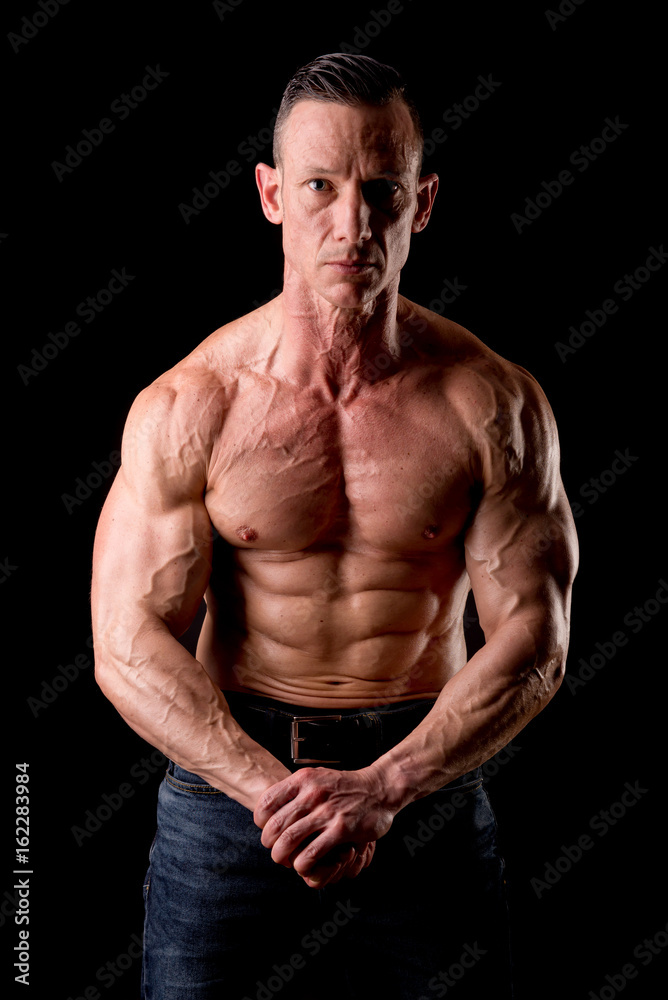 fit muscular man posing isolated on a dark background