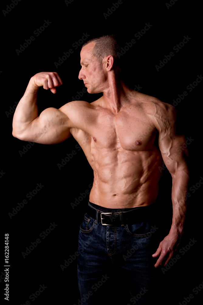 fit muscular man posing isolated on a dark background fit muscular man posing isolated on a dark background
