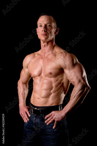 fit muscular man posing isolated on a dark background